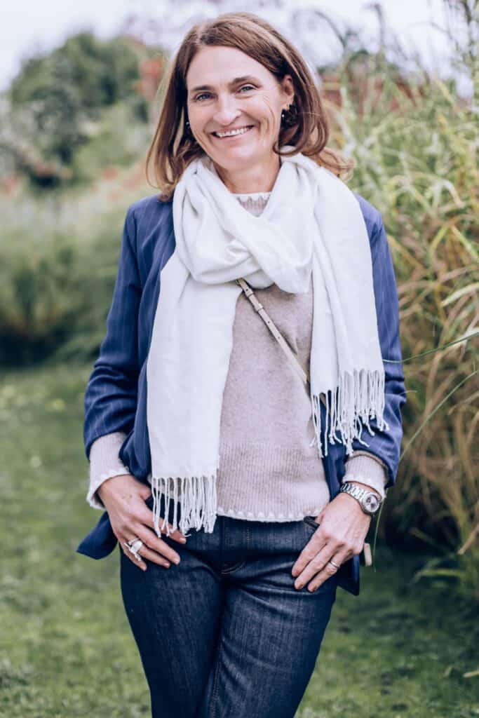 Gertrud Angerer, traumasensible Nervensystem-Coachin, lächelt vor einem Holzzaun.
